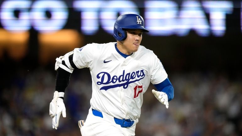 Los Angeles Dodgers' Shohei Ohtani runs to first as he...