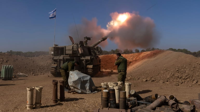 An Israeli mobile artillery unit fires a shell from southern...