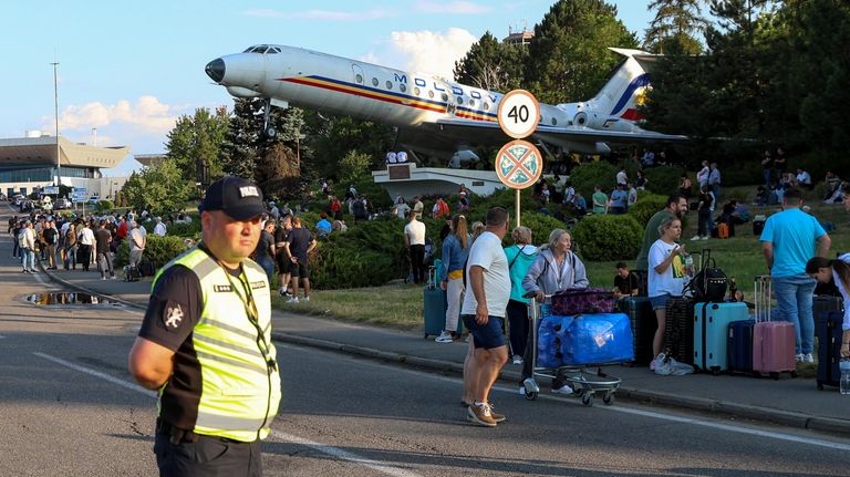 Travelers stand outside the Chisinau airport in Moldova Friday, June...