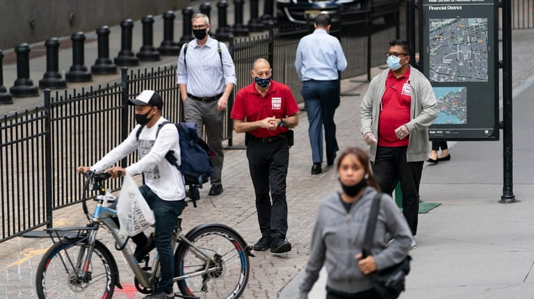 At the start of another workweek, people wearing protective masks Monday in Wall...