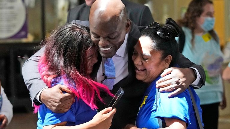 Miami-Dade County Commissioner Kionne McGhee, center, hugs two outdoor workers...