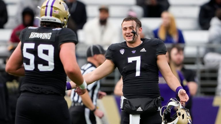 Washington quarterback Will Rogers III greets teammate Zachary Henning (59)...