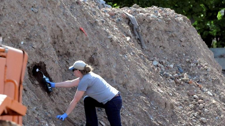 An investigator collects samples of debris at a dumping site...