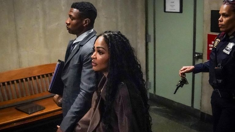 Jonathan Majors, left, leaves the courtroom, during a lunch break...