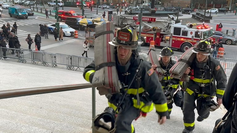 New York firefighters walk up the stairs to the entrance...