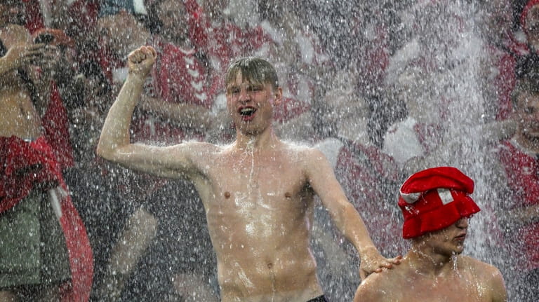 Fans dance in the rain while a round of sixteen...