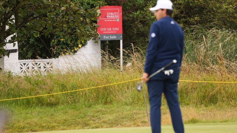 A golfer waits to putt on the 17th green, near...