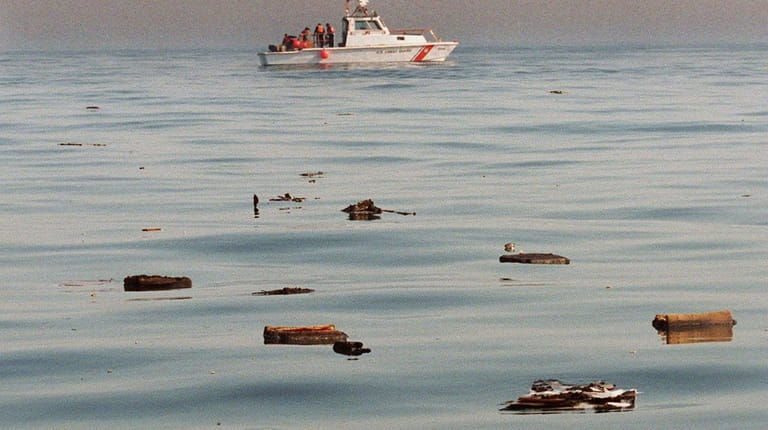 Crewmen aboard a U.S. Coast Guard boat pickup pieces of...