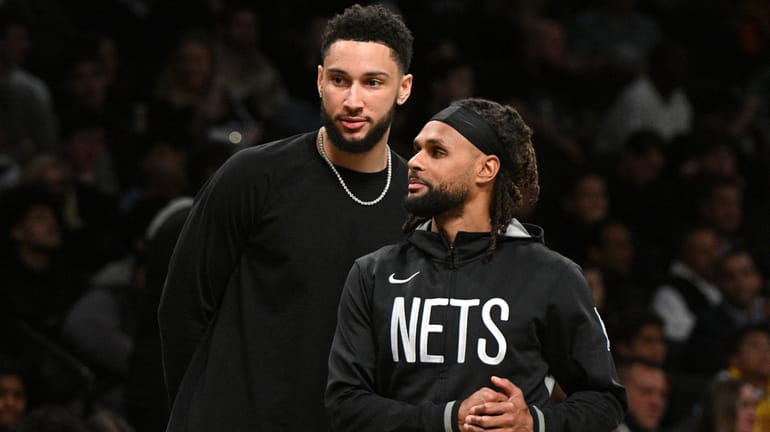 Brooklyn Nets guards Ben Simmons, background, and Patty Mills against...