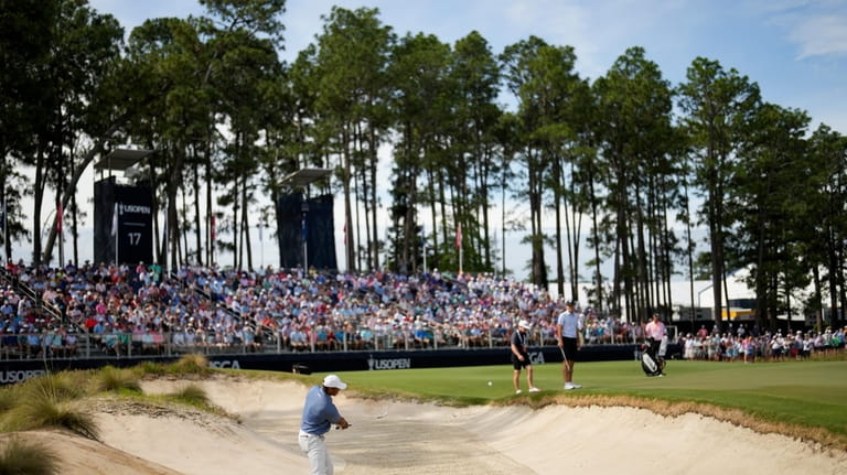 Tiger Woods hits from the bunker on the 17th hole...