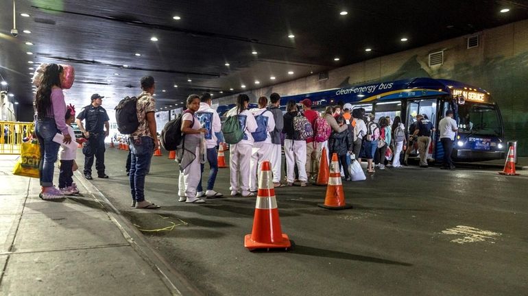 Migrants board a city bus to a shelter intake center...