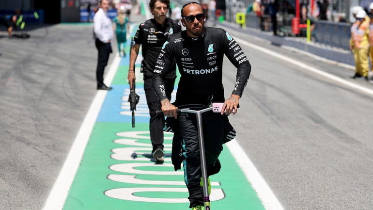 Mercedes driver Lewis Hamilton of Britain rides a scooter outside...