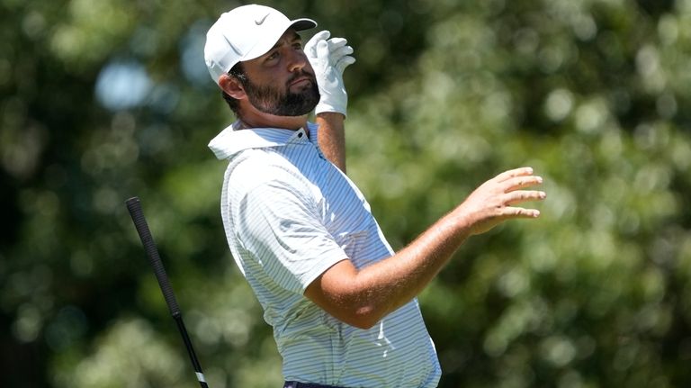 Scottie Scheffler drops his driver after hitting from the seventh...