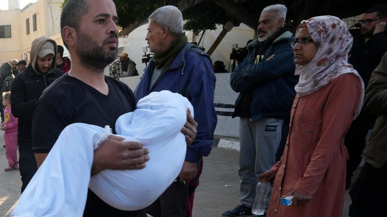 A Palestinian carries a child killed in the Israeli bombardment...
