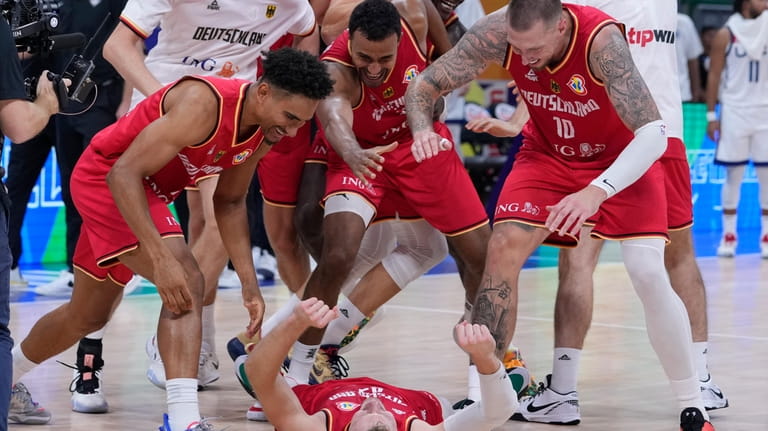 Germany guard Andreas Obst lays on the ground as teammates...