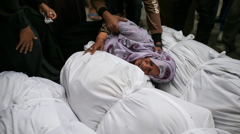 Palestinians mourn over the bodies of relatives killed in an...