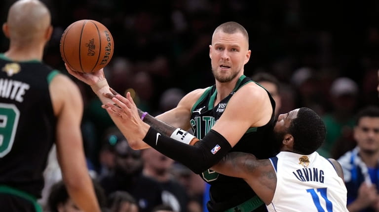 Boston Celtics center Kristaps Porzingis looks to pass while defended...