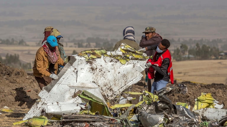 Workers recover debris at the scene of an Ethiopian Airlines...