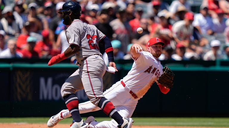 Los Angeles Angels third baseman Brandon Drury, right, throws out...