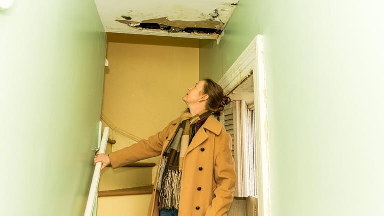 Old Field Village Trustee Rebecca Van Der Bogart inspects damage...