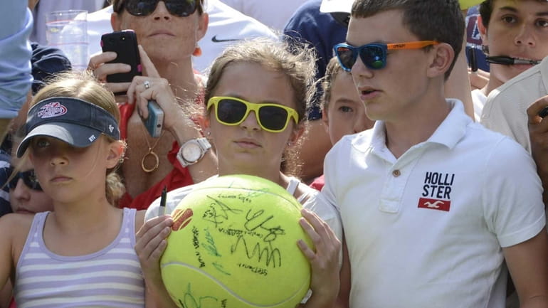 Fans wait court side with large tennis balls waiting for...