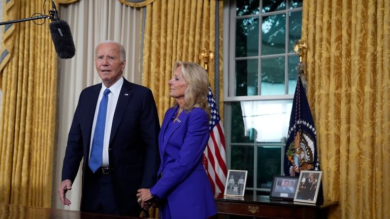 President Joe Biden stands next to first lady Jill Biden...