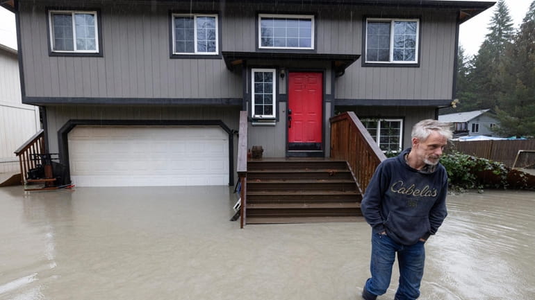 Bernie Crouse wades through water outside his home after the...