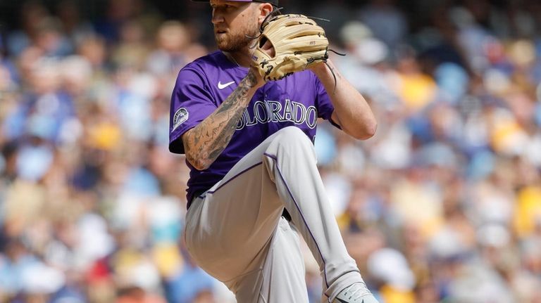 Colorado Rockies pitcher Kyle Freeland winds up to throw to...