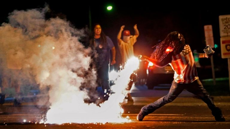 Edward Crawford Jr. returns a tear gas canister fired by...