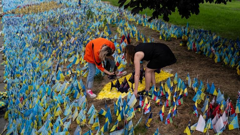 Tetiana Poltorak, left, and Tetiana Artemenko place flags to honor...