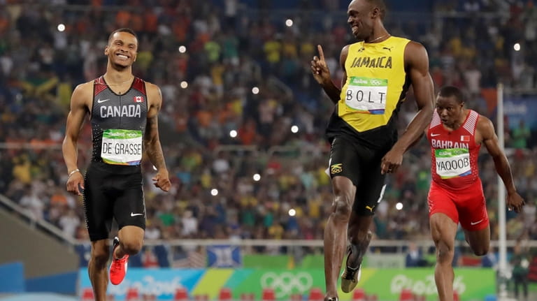 Jamaica's Usain Bolt, right, gestures towards Canada's Andre De Grasse...