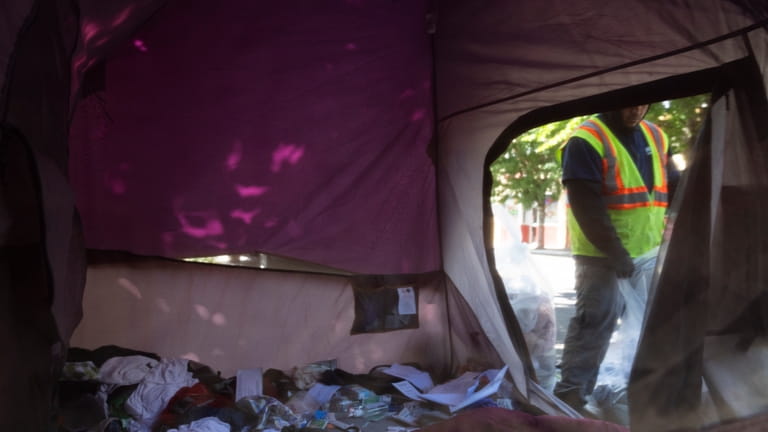 Workers remove contents from a tent after Portland police detained...