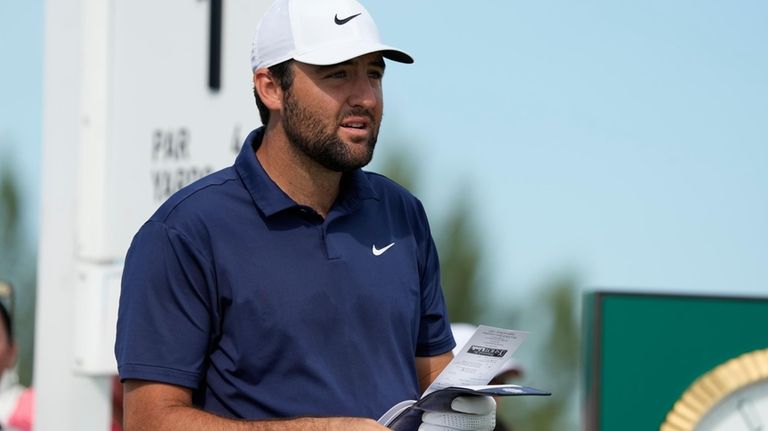 Scottie Scheffler, of the United States, studies his tee shot...