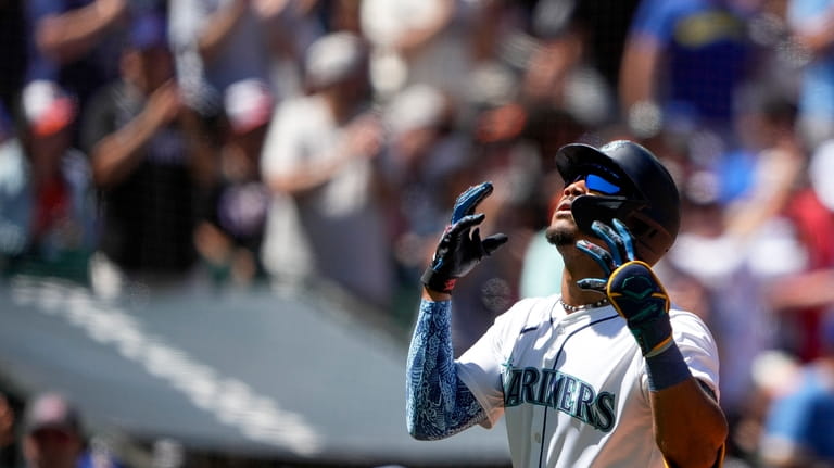 Seattle Mariners' Julio Rodríguez crosses home plate after hitting a...