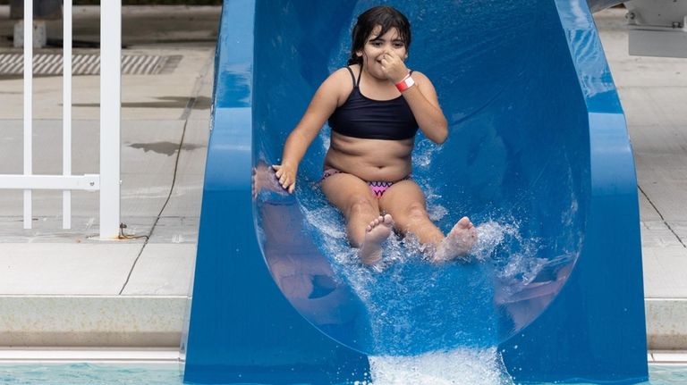 Ashley Portillo, 8, of Brentwood, rides a slide at the...