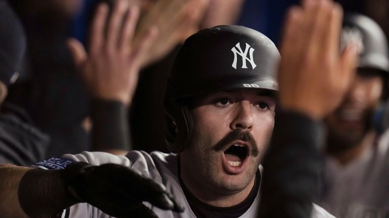 New York Yankees' Austin Wells celebrates in the dugout after...