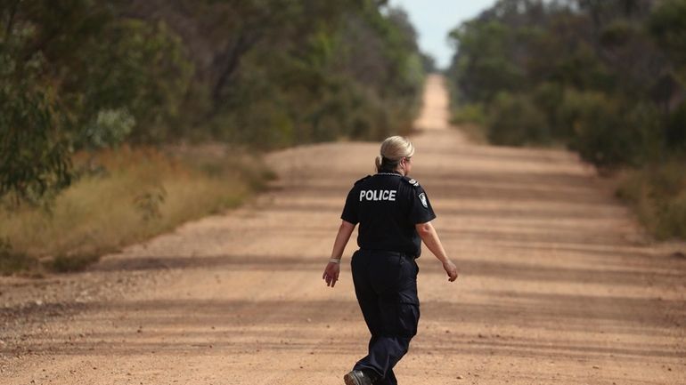 A Police officers walks across a road near the scene...