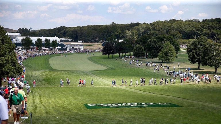 Spectators line and cross the first fairway in between tee...