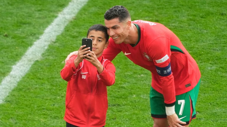 A young pitch invader takes a selfie with Portugal's Cristiano...