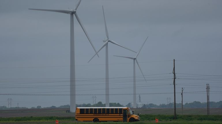 A school bus drives down a road near a field...