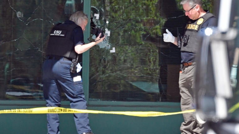 A Louisville Metro Police technician photographs bullet holes in the...