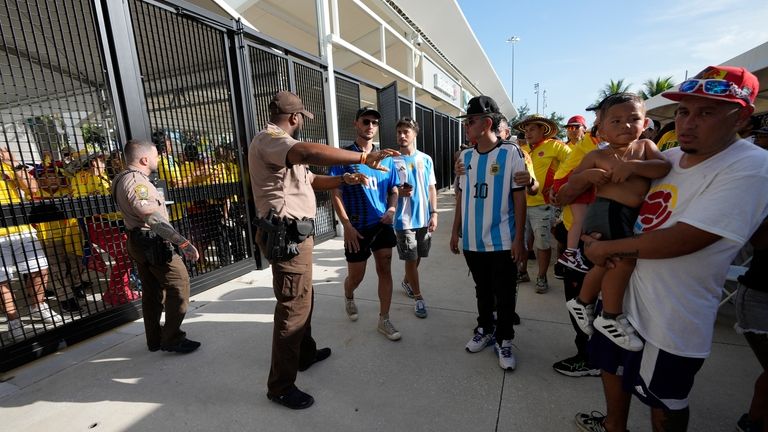 Police agents give instructions to fans outside the stadium prior...