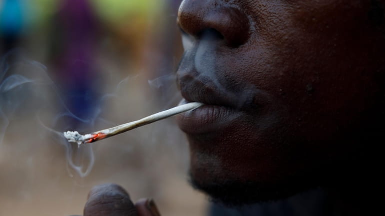 A young man smokes Kush at a hideout in Freetown,...