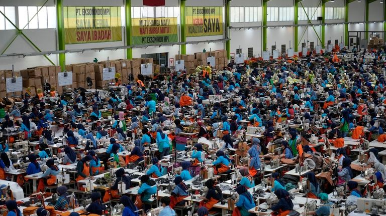 Workers sit in their stations at a factory belonging to...