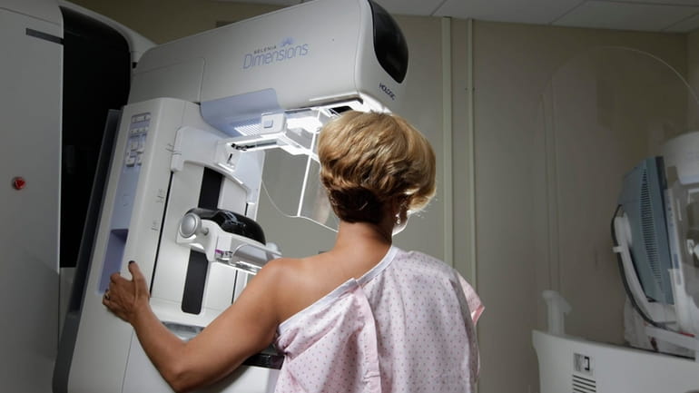 A mammography patient receives a breast screening with the Hologic...