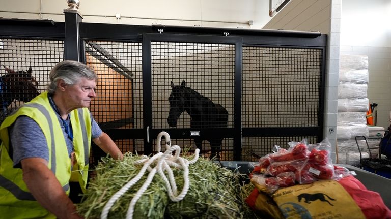 A staff member pushes a cart full of supplies past...