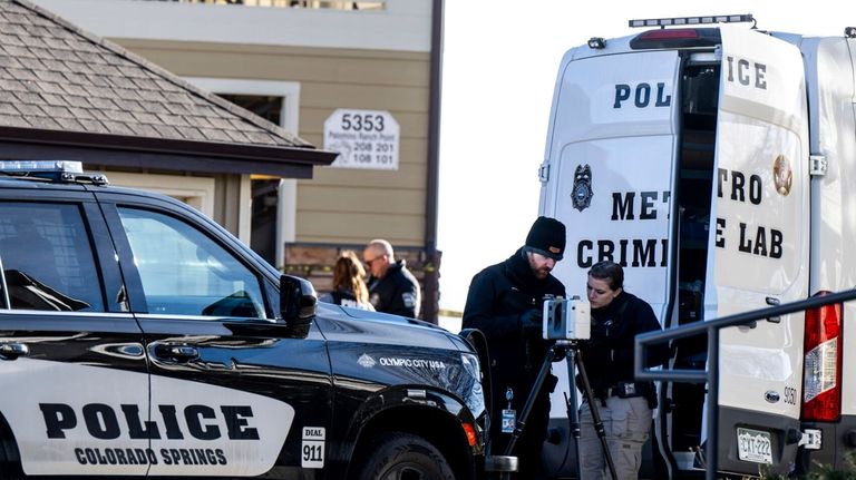 Colorado Springs Police Department investigators and officers work on the...