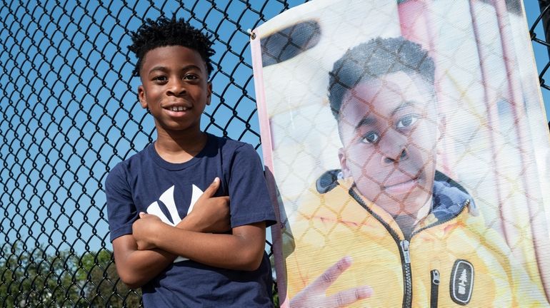 Micah Elliot poses next to his banner at Plaza Elementary...