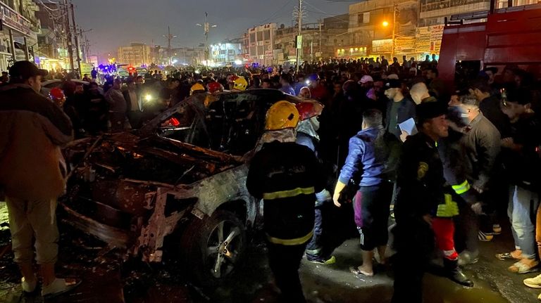 Civil defense members gather at the site of a burned...