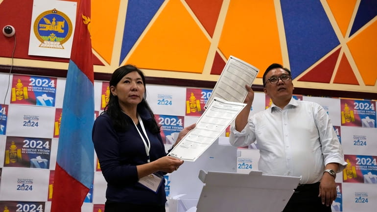Election workers holds up ballots as manual counting begins after...